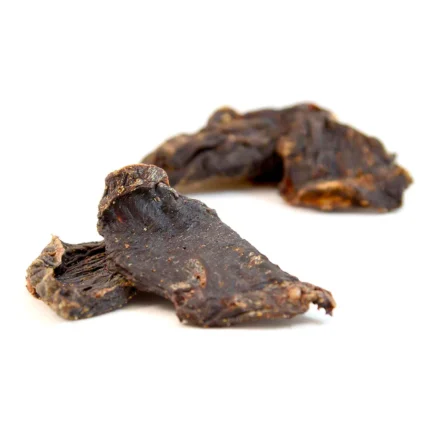 Two strips of dark beef jerky on a white background, showing a chewy texture and meat fibers.