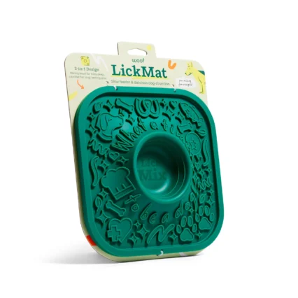 Teal LickMat dog slow-feeder silicone tray with embossed shapes, shown against its packaging featuring a dog illustration and the LickMat branding.